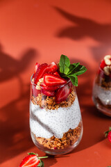 Granola with yogurt, chia and strawberries in a glass on a bright background