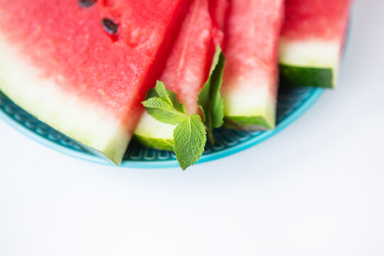 Close-up of fresh slices of watermelon along with mint leaves lie on a plate. Summer food.
