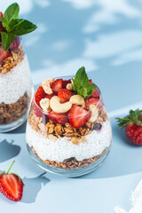 Granola with yogurt, chia and strawberries in a glass on a bright background
