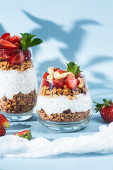 Granola with yogurt, chia and strawberries in a glass on a bright background