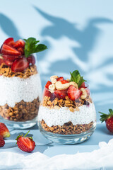Granola with yogurt, chia and strawberries in a glass on a bright background