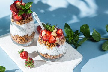 Granola with yogurt, chia and strawberries in a glass on a bright background