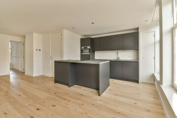a kitchen and living room in an apartment with wood floors, white walls and black cabinetry on the wall
