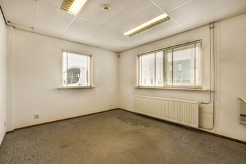 an empty room with white walls and grey carpet on the floor, there is a window that has blinds in it