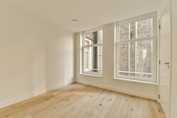 an empty room with white walls and wood flooring, there is a large window in the wall has a brick pattern on it