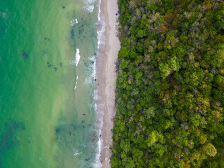 From above, the mesmerizing beach unfolded with golden sand caressed by turquoise waves. Lush green...