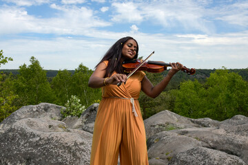 Lovely black woman playing violin in the forest