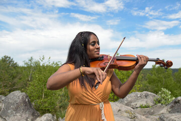 Lovely black woman playing violin in the forest