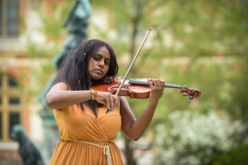 Lovely black woman playing violin in a park
