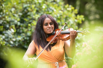 Lovely black woman playing violin in a park