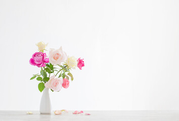 pink and white roses in white ceramic vase on white background