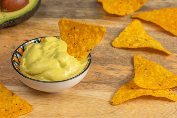 Avocado Cream Sauce for tortilla chips in ceramic bowl over wooden background.