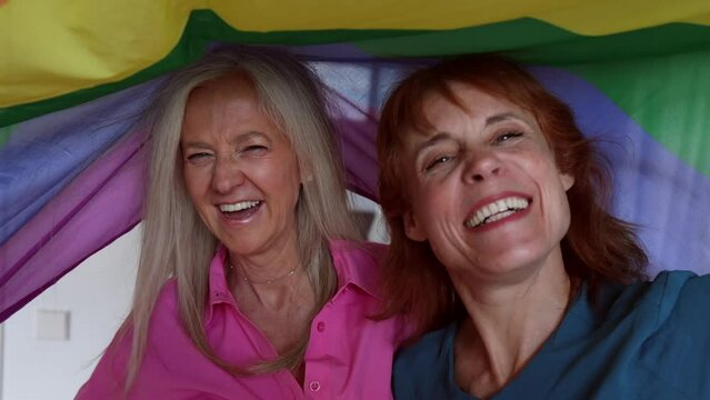two senior mature women hoist the gay rainbow flag. I support the lgbti, gay, homosexual, bisexual, lesbian, trans, non-binary community. Fight for freedom and rights