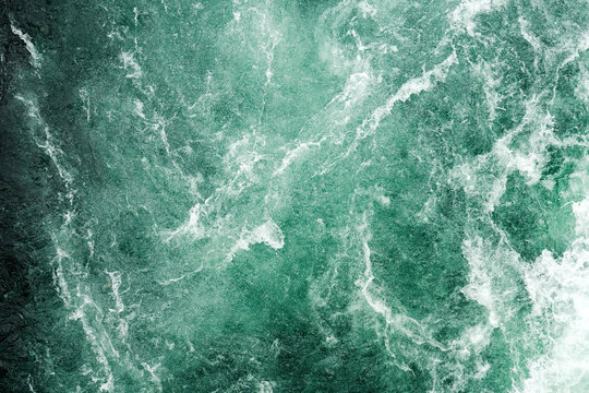 Texture of dark stormy water surface with white waves and splashes. Abstract nature backgrounds