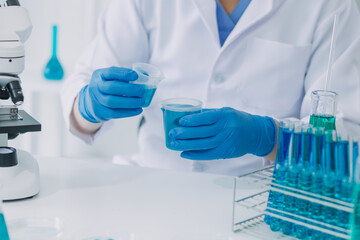 Fototapeta premium medical or scientific researcher researching and experimenting Multi-colored solution, vial and microscope In the laboratory or in the laboratory by wearing blue gloves and white clothing completely.