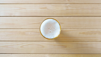 Beer in a glass on a light wooden background with copy space
