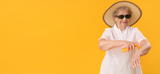 Senior woman applying sunscreen cream onto skin against yellow background with space for text