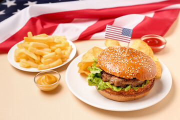 Plates with tasty burger, french fries, potato chips, sauces and American flag on color background. Memorial Day celebration
