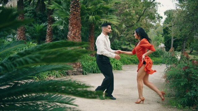 Professional artists dancing latin american dance in garden. Partners performing