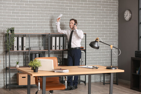 Young businessman throwing paper plane in office