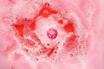 Bath bomb dissolving in pink water