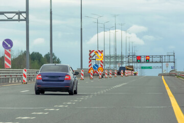 Roadworks, large bright mobile sign with stripes, detour direction. The blue car is moving into a free lane.