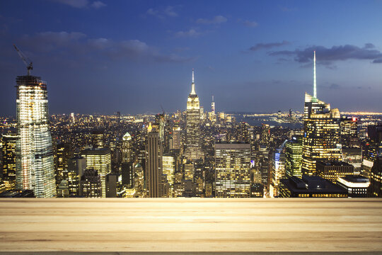 Empty wooden table top with beautiful New York skyscrapers at evening on background, mock up