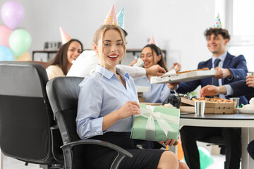 Young woman with gift at birthday party in office