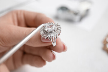Female jeweler making ring on white table, closeup