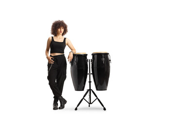 Full length portrait of a young female leaning on conga drums