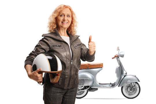 Mature woman with a scooter holding a helmet and gesturing thumbs up