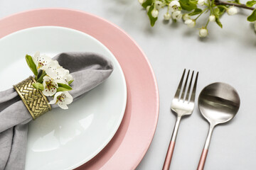 Beautiful table setting with blooming tree branches on grey background
