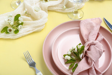 Beautiful table setting with blooming tree branches on yellow background