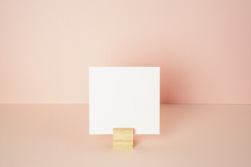 White blank memo pad with wooden holder on pink desk. pink wall background. copy space