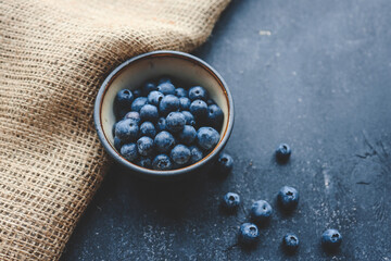 Fototapeta na wymiar Fresh juicy blueberries in plates on a dark background top view
