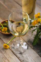Glass of dandelion wine on wooden background