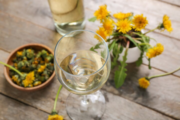 Glass of dandelion wine on wooden background