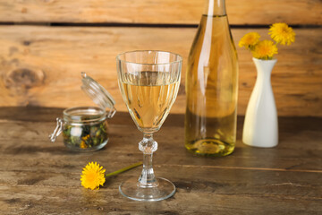 Bottle and glass of dandelion wine on wooden table