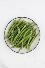 Green beans are raw in a plate. Healthy eating.