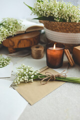 Festive concept, lily of the valley bouquet, gift box , burning candle and letter