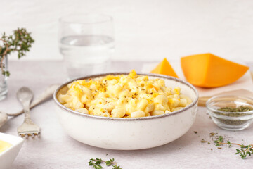 Bowl of tasty Italian pasta with Cheddar cheese on light background