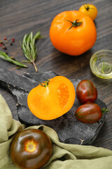 Board with different fresh tomatoes on wooden background