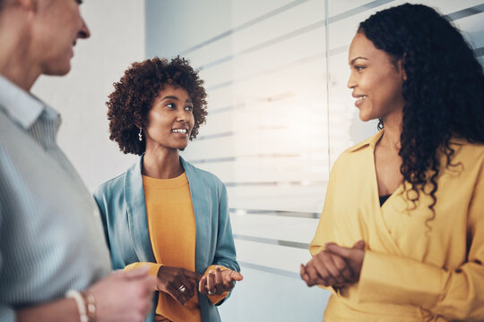 Three diverse businesswomen smiling while talking in an office
