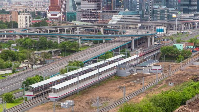Small Ring of the Moscow Railways timelapse. Orbital railway in Moscow, Russia. Shelepikha Station aerial top view with traffic on third transport ring and skyscrapers behind