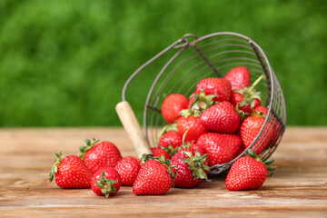 Basket with fresh strawberry on wooden table outdoors