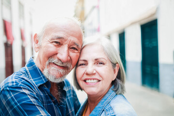 Happy senior couple having fun with city in background during summer travel vacations - Elderly community lifestyle - Focus on man face