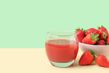 Glass of juice and bowl with strawberry on beige table