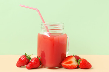 Mason jar of tasty strawberry juice on color background