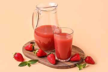 Board with jug and glass of tasty strawberry juice on orange background