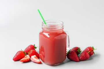 Mason jar of tasty strawberry juice on grey background